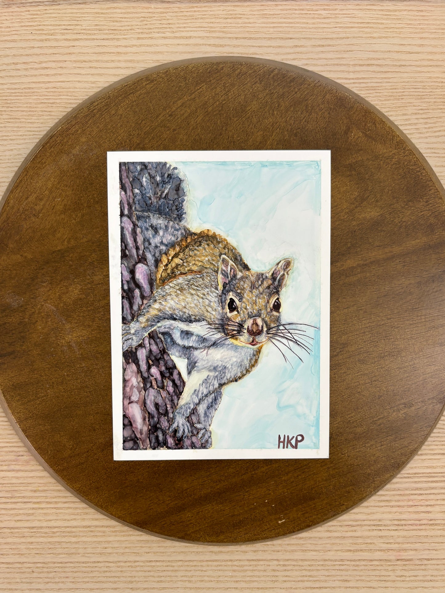 Painting of a squirrel displayed on a wooden plate